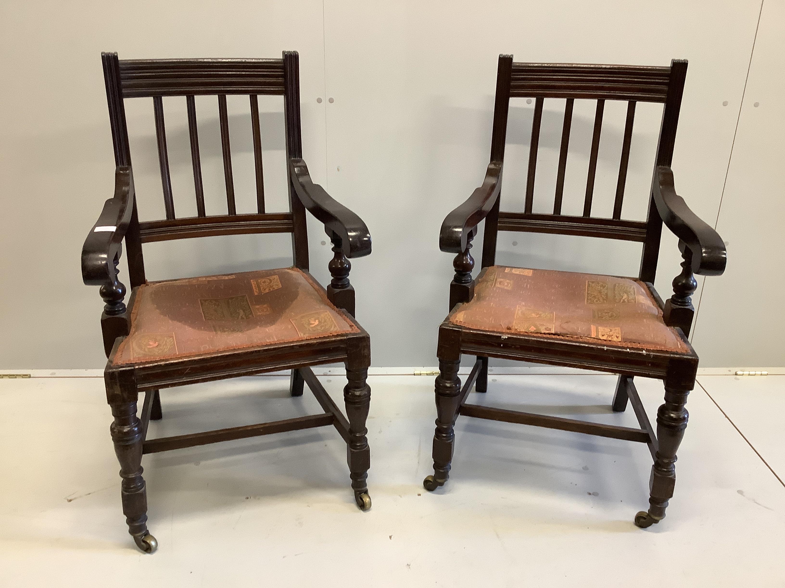 A pair of 1920's mahogany rail back elbow chairs, raised on castors, width 56cm, depth 47cm, height 104cm